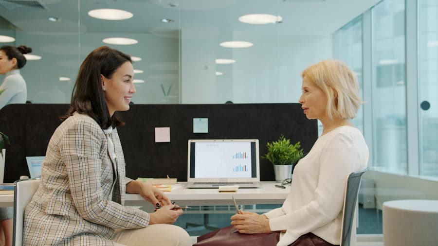 Two colleagues talking across a desk in a bright office
